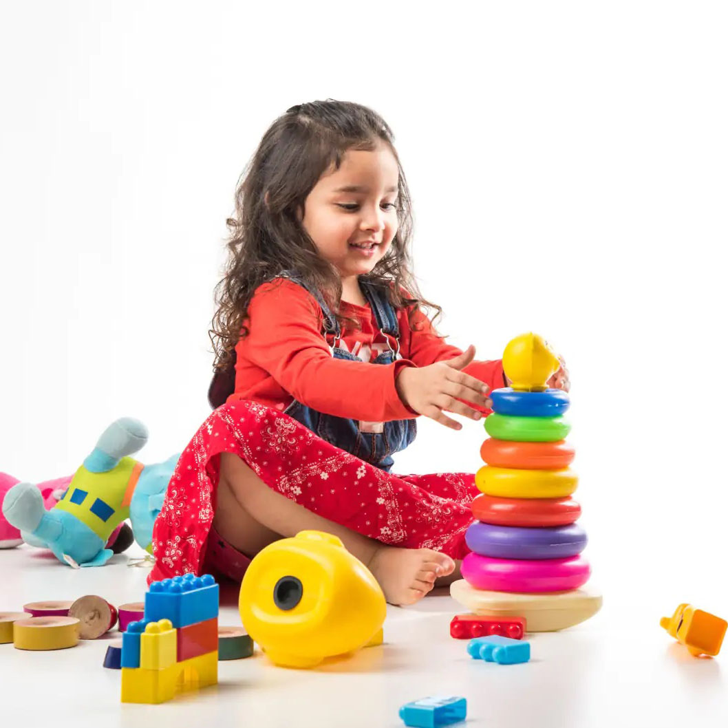 A young girl happily plays with K square edutainment  toys on a white background.