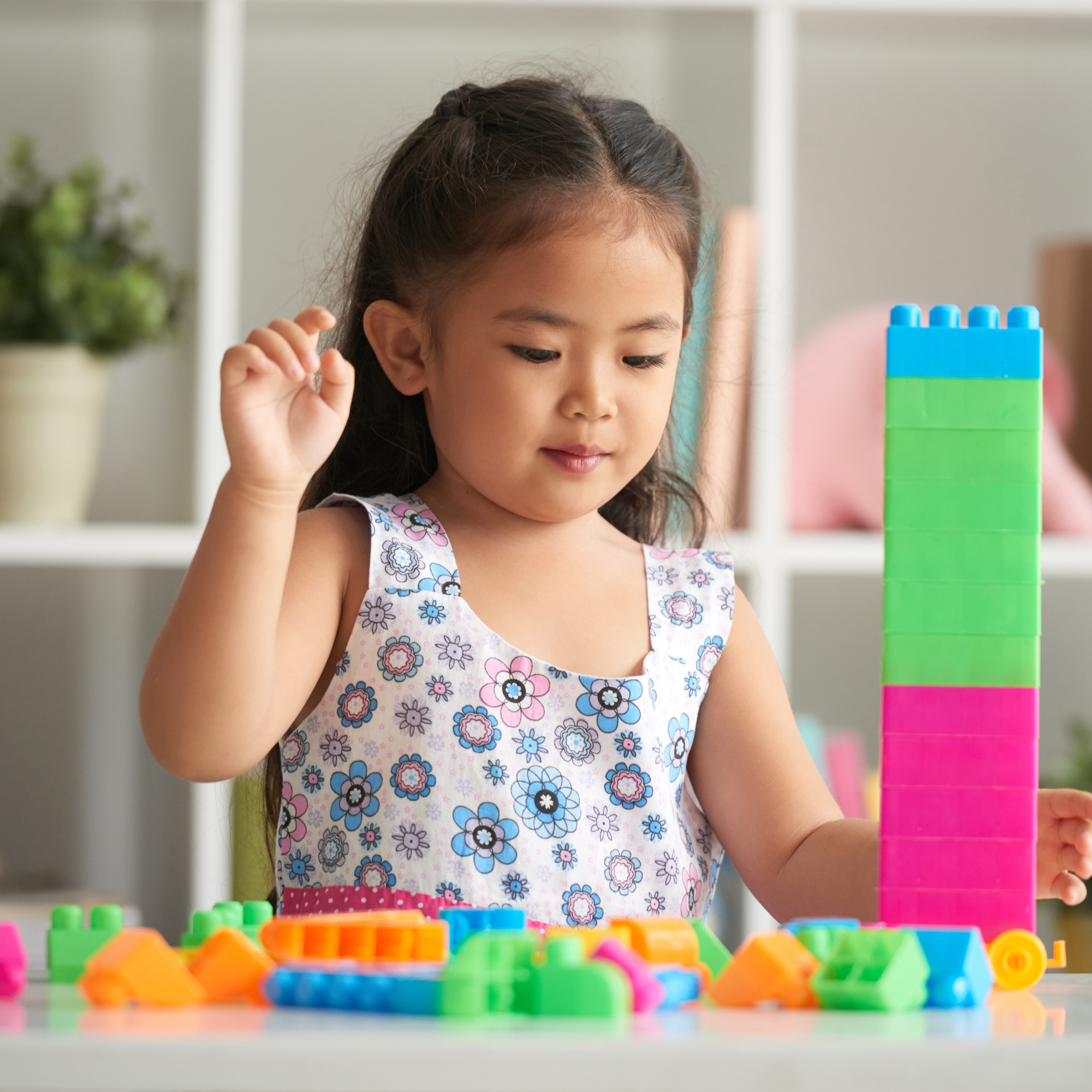 A young girl happily playing with colorful K square edutainment blocks on the floor