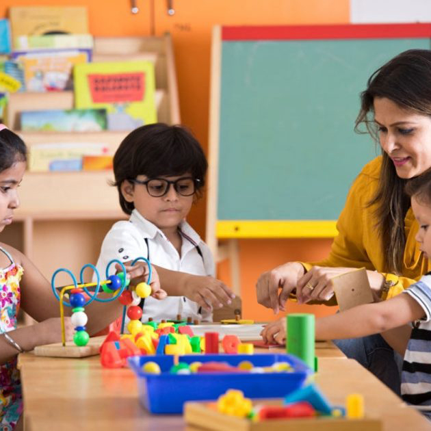 A woman was instructing children at a classroom table, engaging them in a learning activity.